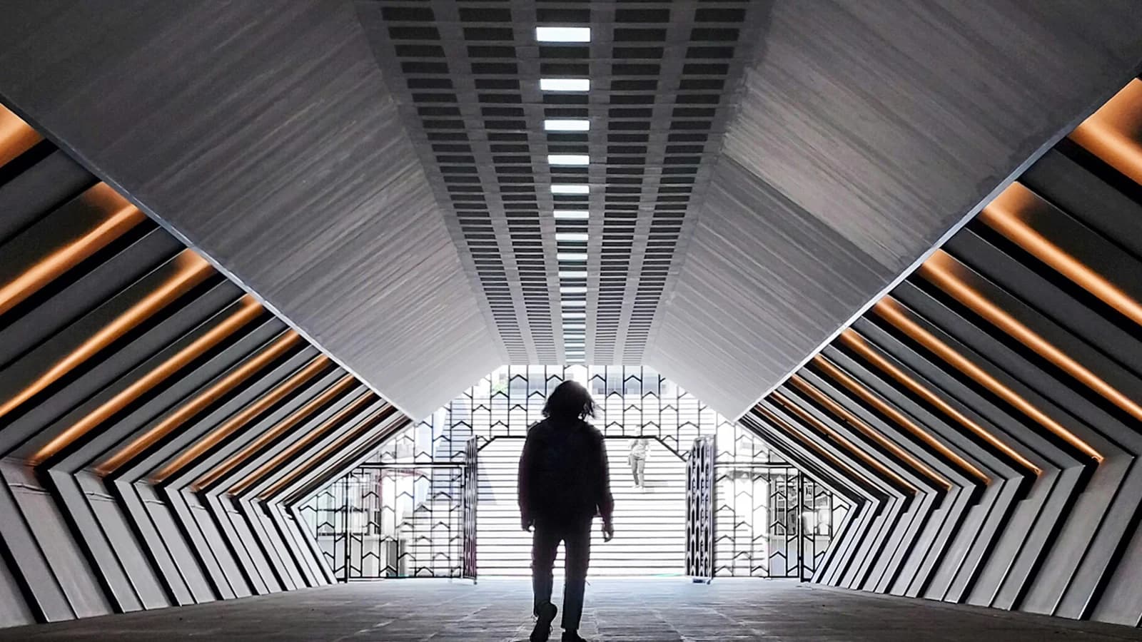 A person stands in a passage facing daylight at the far end.